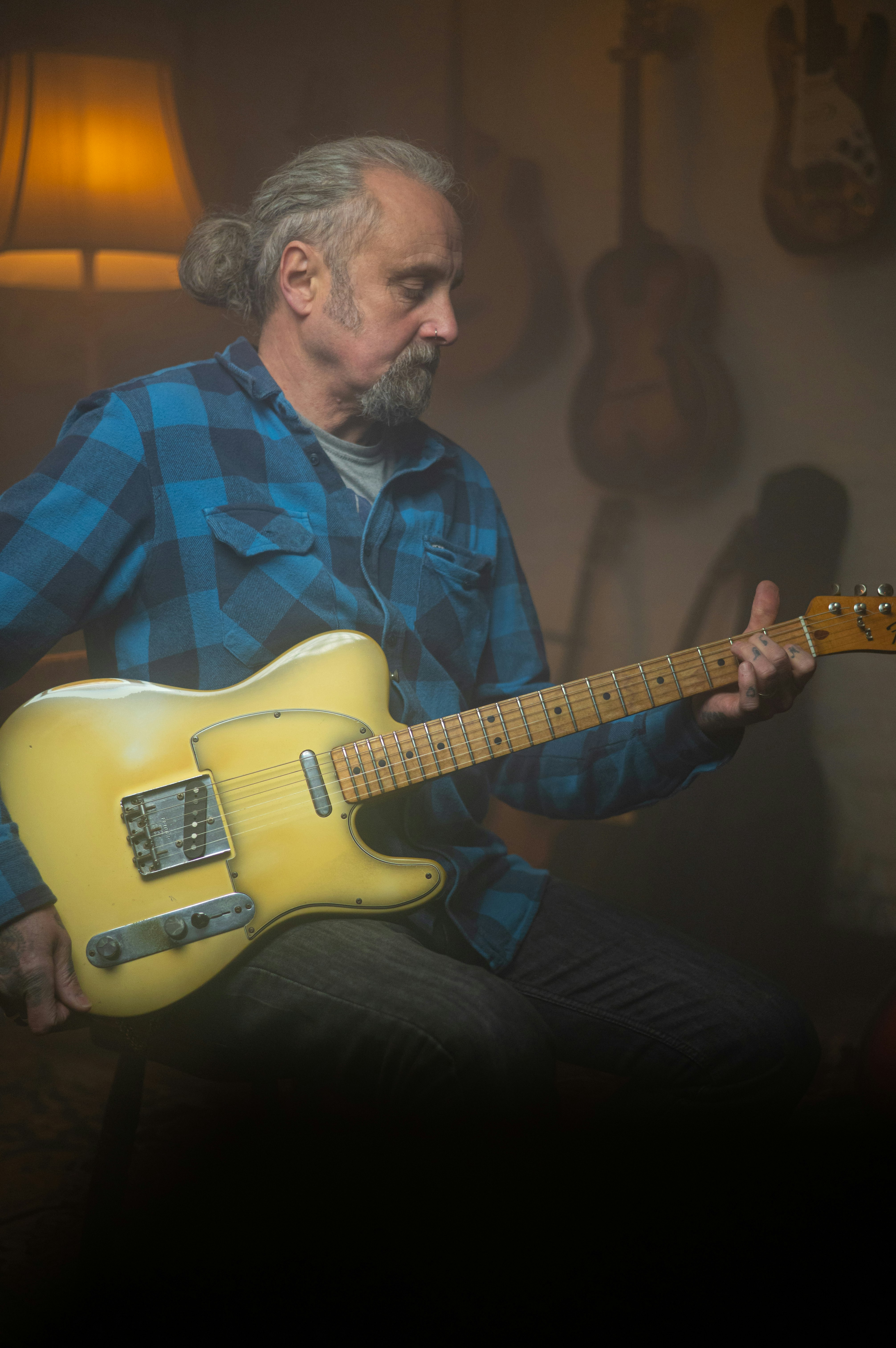 man in blue and black plaid button up shirt playing yellow electric guitar